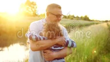 年迈的祖父和慈爱的孙子微笑着拥抱在户外，在河岸上。 两代人